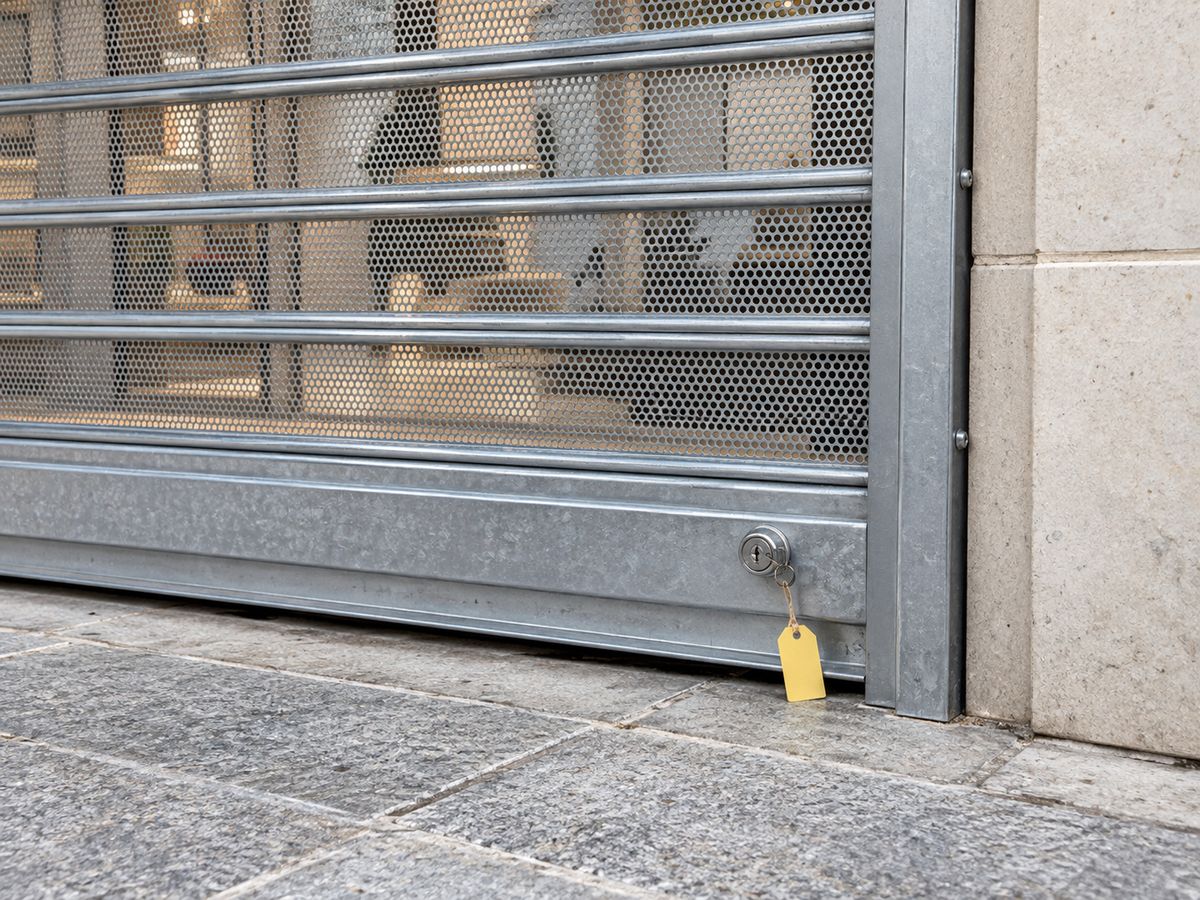 Cierre metálico microperforado con guía y cerradura en un local comercial